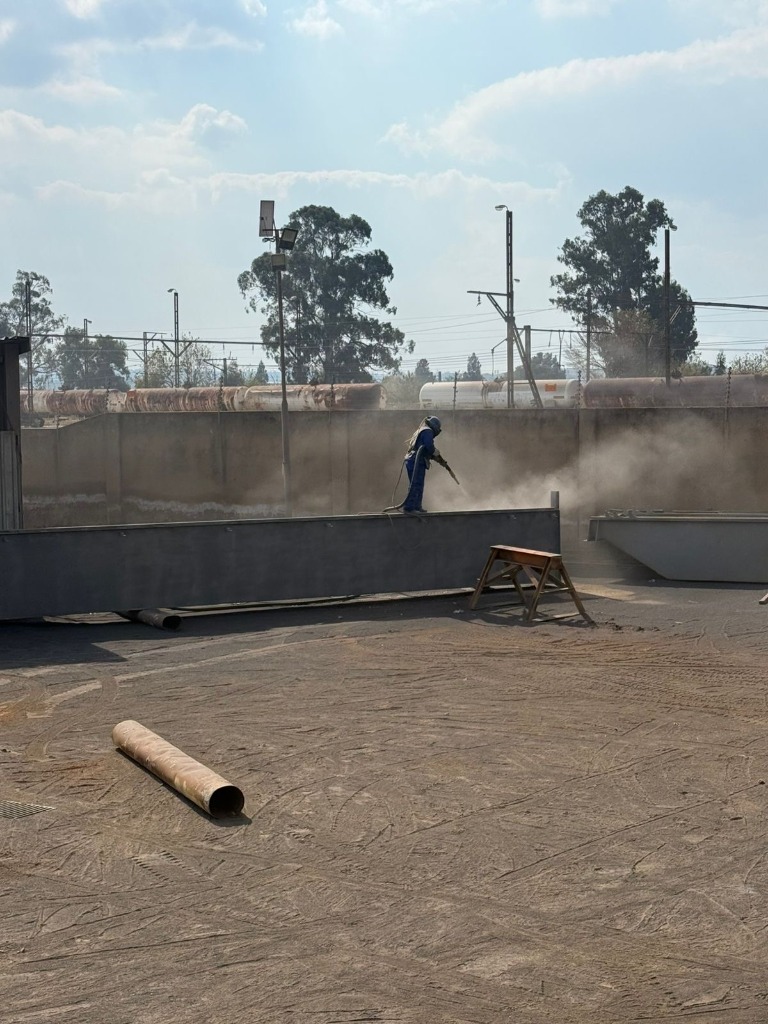 Rust Busters operator abrasive blasting a structural steel girder